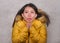 Young beautiful Asian Chinese woman feeling cold and chilly freezing feeling cold in Winter weather wearing yellow jacket with fur