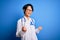 Young beautiful asian doctor girl wearing stethoscope and coat with blue cancer ribbon excited for success with arms raised and