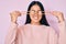 Young beautiful asian girl puting sushi on eyes using chopsticks smiling with a happy and cool smile on face