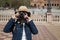 Young and beautiful asian tourist taking picture with reflex camera in front of the camera during her vacation trip