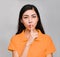 Young beautiful asian woman,long black hair, wore orange t shirt, Pointing finger on mouth, Show The secret face,Do not disturb,
