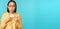 Young beautiful asian woman showing credit card, smiling, choosing bank, standing over blue background