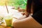 Young beautiful Asian woman are working,drawing or writing on paper with plastic cup of iced green tea and beautiful green nature.