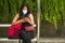 Young beautiful and attractive Asian Chinese tourist woman wearing protective face mask checking hand phone at city bus stop about