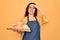 Young beautiful baker woman with blue eyes wearing apron holding tray with bread stressed with hand on head, shocked with shame