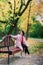 Young beautiful ballerina in fair coat and pointe shoes sit on the bench, rest outdoors