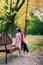 Young beautiful ballerina in fair coat and pointe shoes sit on the bench, rest outdoors