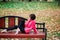 Young beautiful ballerina in fair coat and pointe shoes sit on the bench, rest outdoors