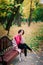 Young beautiful ballerina in fair coat and pointe shoes sit on the bench, rest outdoors