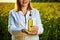 A young beautiful biologist or agronomist examines the quality of rapeseed oil on a rape field. Agribusiness concept