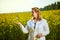 A young beautiful biologist or agronomist examines the quality of rapeseed oil on a rape field. Agribusiness concept