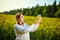 A young beautiful biologist or agronomist examines the quality of rapeseed oil on a rape field. Agribusiness concept