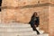 young and beautiful black latin woman wearing black clothes and sunglasses is sitting on the steps of the most important square in