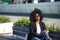 Young, beautiful, black woman with afro hair, with jacket and sunglasses sitting on a bench, looking at infinity, relaxed,