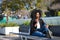 Young, beautiful, black woman with afro hair, wearing a jacket, with the temple of her glasses on her mouth, pensive, sitting on a