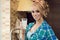 Young beautiful blond housewife in the kitchen holding a glass of milk and smiling