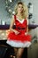 Young beautiful blond woman dressed as Santas Helper in red dress and fishnet hosiery posing in Christmas decorated interior