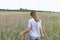 Young beautiful blond woman in purple shirt from behind walking in the meadow among flowers of fireweed