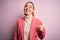 Young beautiful blonde businesswoman with blue eyes wearing elegant pink jacket doing happy thumbs up gesture with hand