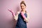 Young beautiful blonde cleaner woman doing housework wearing arpon and gloves amazed and smiling to the camera while presenting