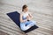 Young beautiful blonde girl smiling, practicing yoga outside.