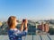 Young beautiful blonde girl taking pictures of the city with a camera on a rooftop in Moscow, Russia.