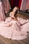 Young beautiful blonde girl wearing a full-length draped one shoulder pale pink satin slit prom ball gown decorated with