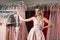 Young beautiful blonde girl wearing a full-length draped one shoulder pale pink satin slit prom ball gown decorated with