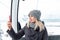 A young beautiful blonde girl in winter clothes and a gray knitted hat sits in the gondola lift cabin in the mining resort and