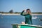 Young, beautiful, blonde, green-eyed, young woman in a green dress, sitting in a boat, covering herself from the sun with her hand