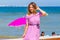 Young beautiful blonde hair curvy model posing on the beach wearing pink striped dress