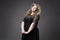 Young beautiful blonde plus size model in black dres, xxl woman portrait on gray studio background