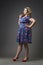 Young beautiful blonde plus size model in dress and shoes, xxl woman on gray studio background