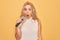 Young beautiful blonde singer woman singing using microphone over yellow background scared and amazed with open mouth for