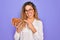 Young beautiful blonde woman with blue eyes holding bowl with healthy almond snack very happy pointing with hand and finger