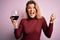 Young beautiful blonde woman drinking glasse of red wine over isolated pink background screaming proud and celebrating victory and