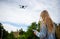 Young beautiful blonde woman piloting a drone holding a remote control