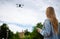 Young beautiful blonde woman piloting a drone holding a remote control