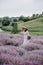 Young beautiful blonde woman in a romantic dress, a straw hat and a basket of flowers is walking in a lavender field. Soft