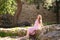 Young, beautiful blonde woman sitting on a large rock in the courtyard of the fortress, a medieval castle in Spain. The woman is