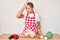 Young beautiful blonde woman wearing apron cooking chicken surprised with hand on head for mistake, remember error