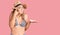 Young beautiful blonde woman wearing bikini and hat confused and annoyed with open palm showing copy space and pointing finger to