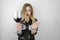 Young beautiful blonde woman wearing black leather jacket drinks wine and shows handcuffed arms on isolated white