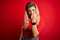 Young beautiful blonde woman wearing casual t-shirt standing over isolated red background Showing middle finger, impolite and rude