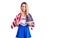 Young beautiful blonde woman wearing cheerleader uniform and united states flag thinking attitude and sober expression looking