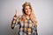 Young beautiful blonde woman wearing golden crown of queen over isolated white background doing happy thumbs up gesture with hand