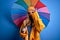 Young beautiful blonde woman wearing raincoat for rainy weather holding colorful umbrella with happy face smiling doing ok sign