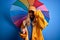 Young beautiful blonde woman wearing raincoat for rainy weather holding colorful umbrella stressed with hand on head, shocked with