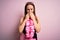 Young beautiful blonde woman wearing swimsuit and floral Hawaiian lei over pink background laughing and embarrassed giggle