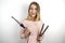 Young beautiful blonde woman wearing trendy pink dress holding curling iron and hair streightener on isolated white